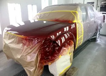 A red truck is being painted in a paint booth.