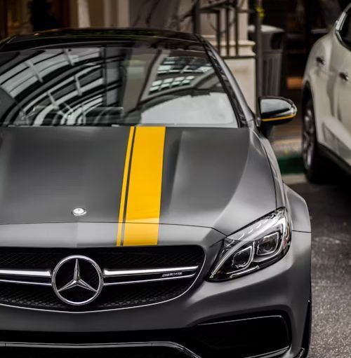 Gray Mercedes-AMG with yellow stripe, parked outside.