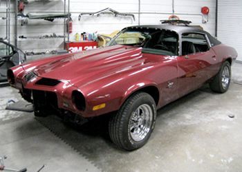 a red car is sitting in a garage with the hood up