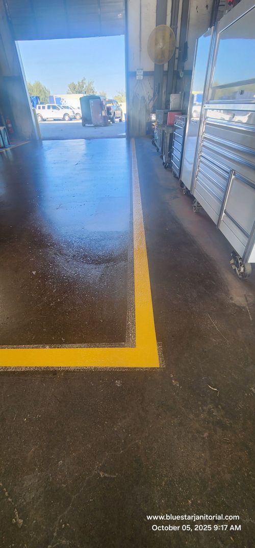 Wet sidewalk with a bright yellow painted line beside a building and outdoor seating area.