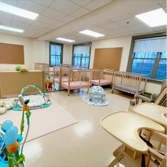 Daycare room with baby cribs, play area, and high chairs.