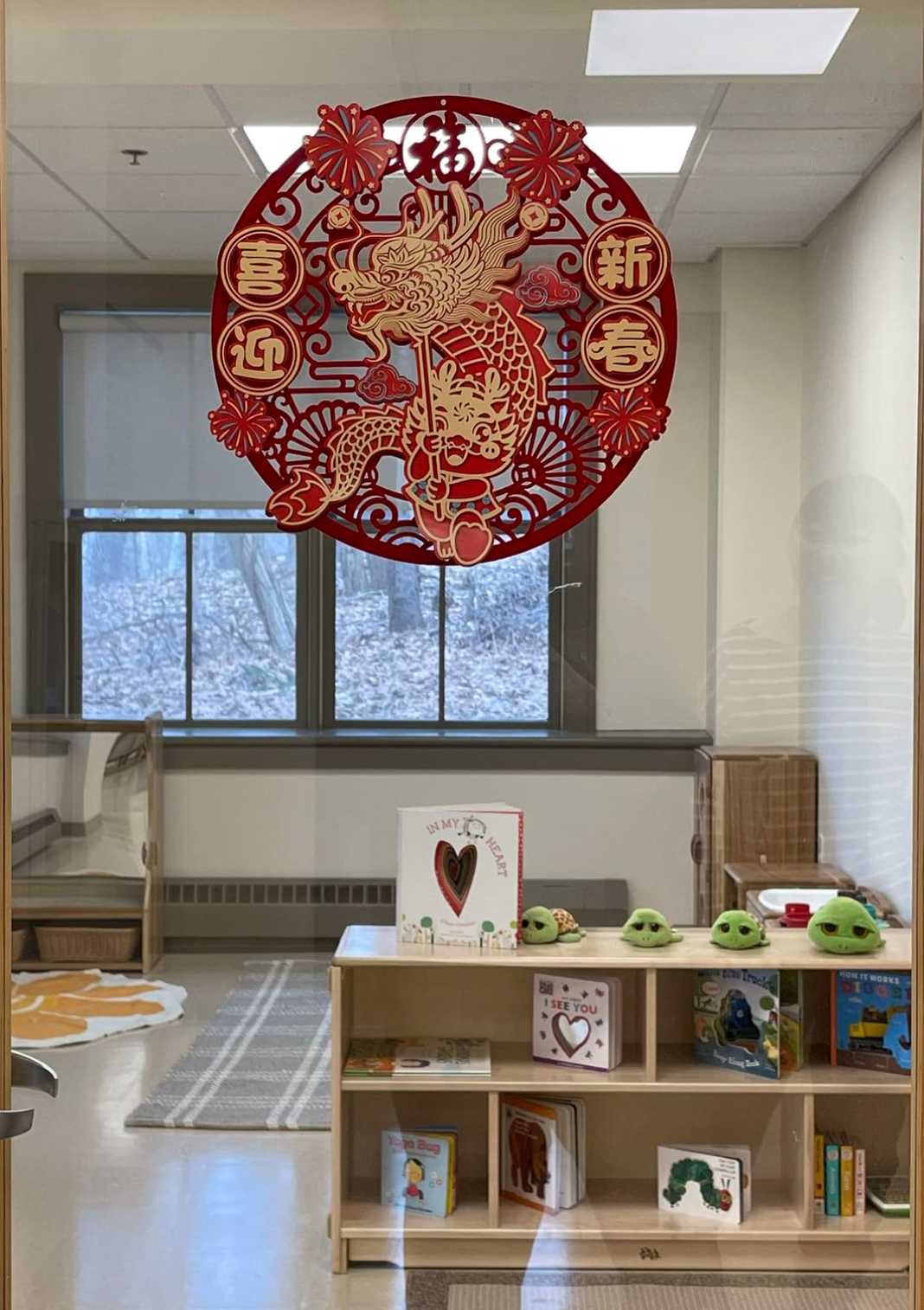 Red paper cut-out decoration in a window with a bookshelf and reading corner visible inside.