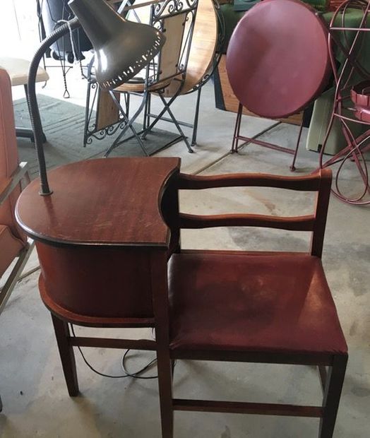 Side table with built-in chair, dark wood with a lamp. Chair has burgundy seat, various outdoor furniture in background. Side table with built-in chair, dark wood with a lamp. Chair has burgundy seat, various outdoor furniture in background.