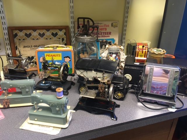 Collection of vintage toys and appliances, including sewing machines, a toaster, and a Peanuts lunchbox.