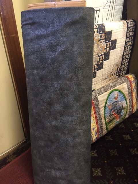 Tall navy blue upholstered cushion leaning against quilted chairs indoors