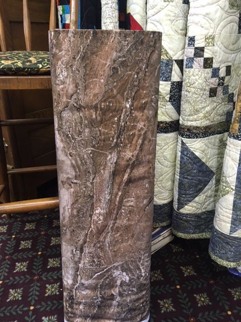 Tall brown marbled decorative vase standing on a patterned carpet indoors