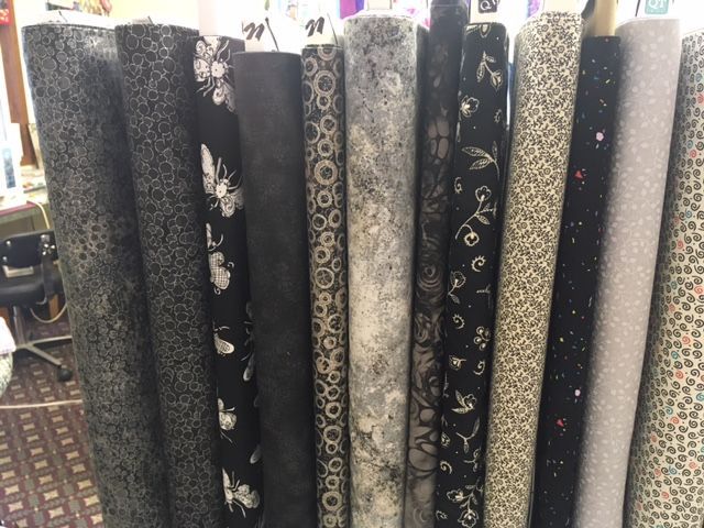 Rolled rugs in assorted dark and patterned designs standing upright in a store display