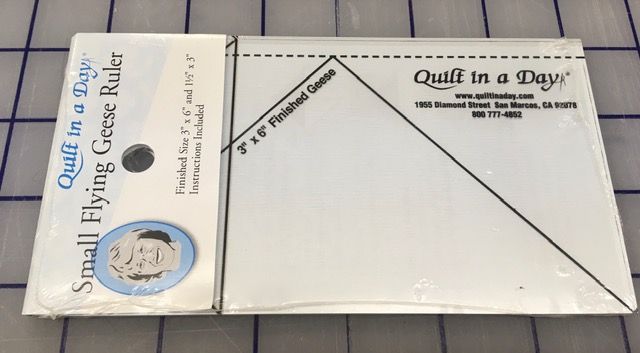 Two white model airplane kits in plastic wrap on a table, labeled “Quilt in a Day” and “Small Flying Red.”