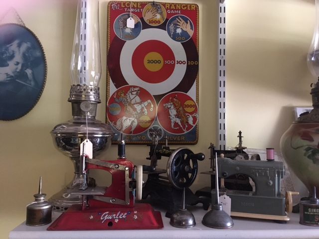 Vintage tabletop display with a red machine, silver lamp, and target poster on a shelf.