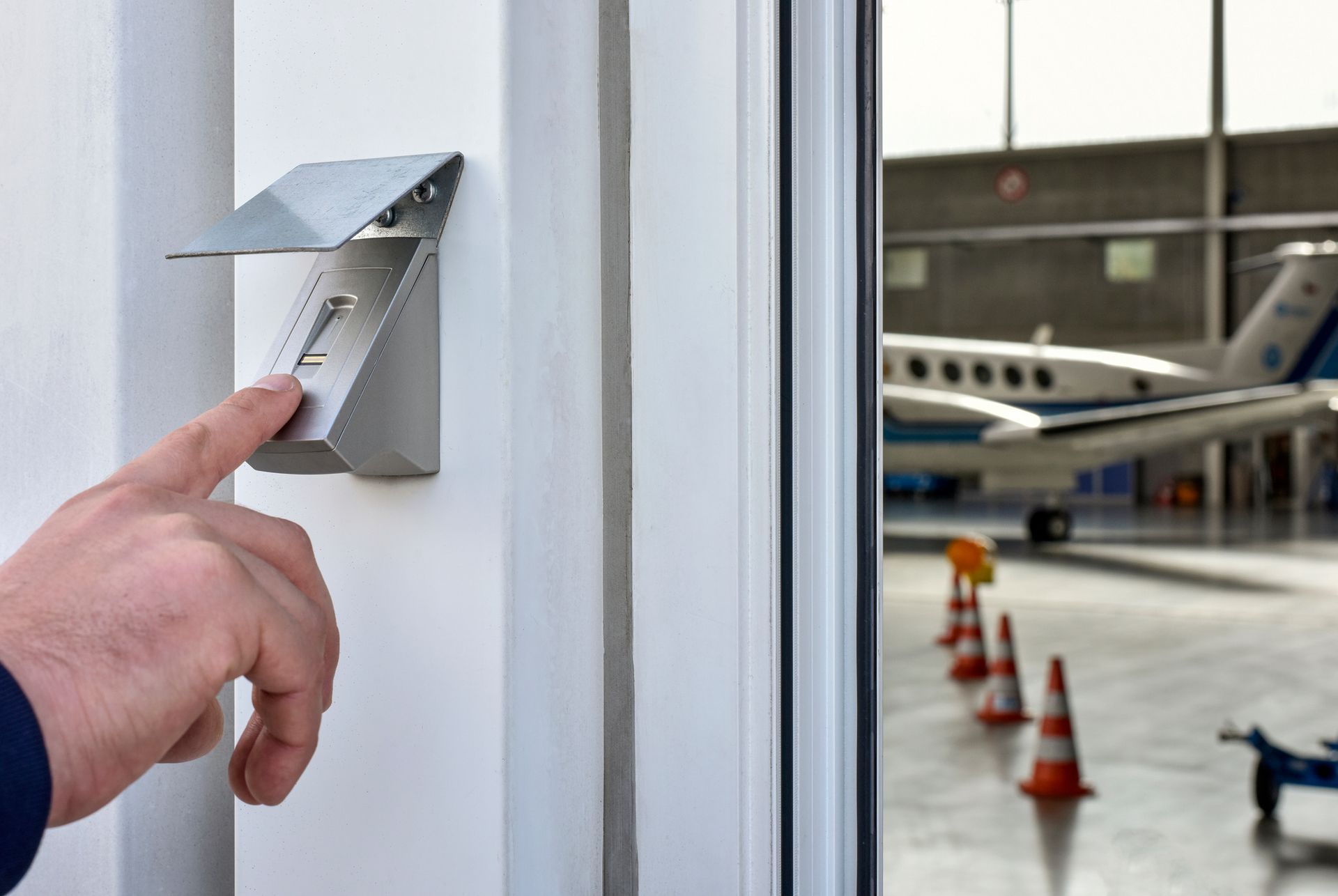 A person is opening a door with a plane in the background
