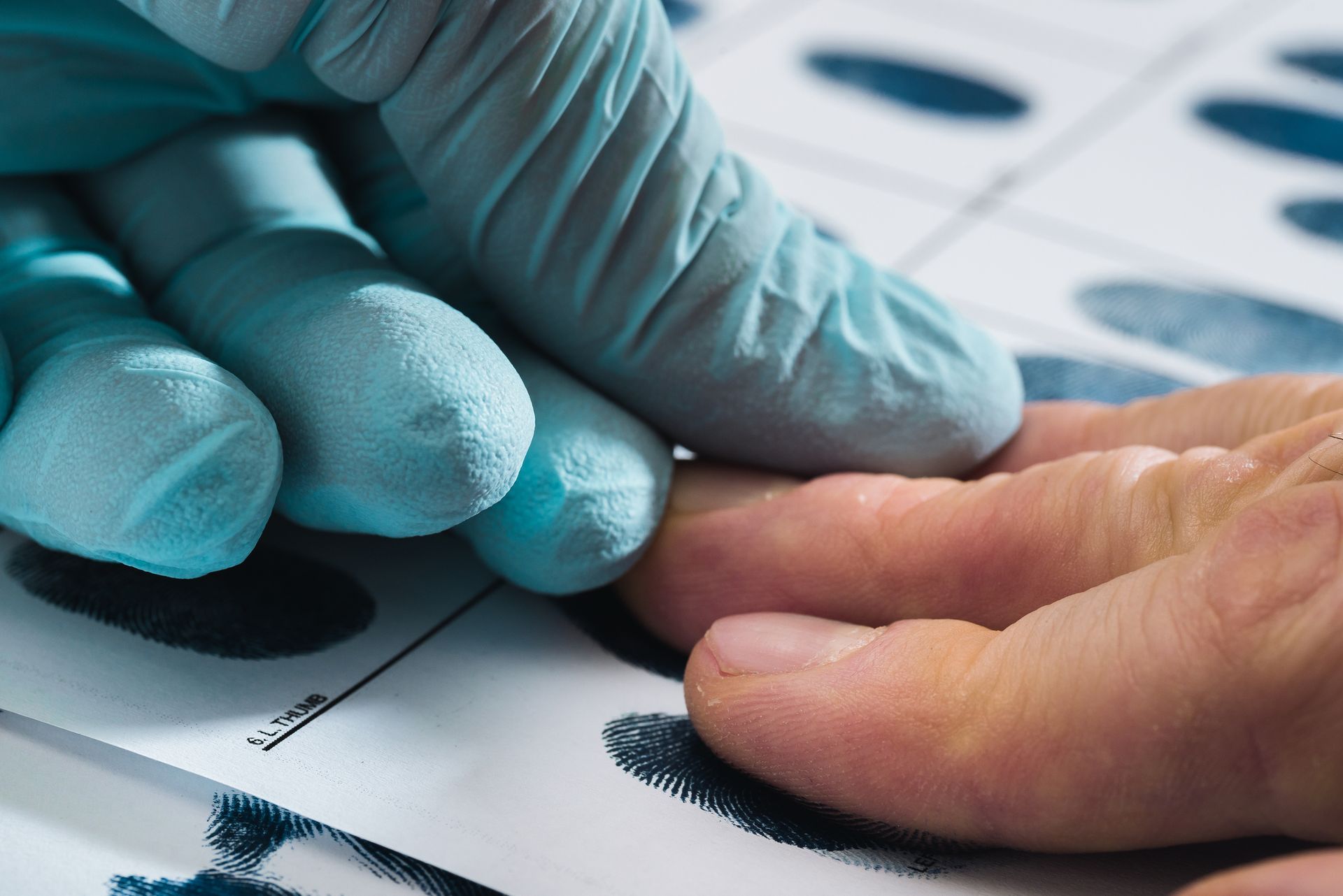 A person wearing blue gloves is taking a finger print