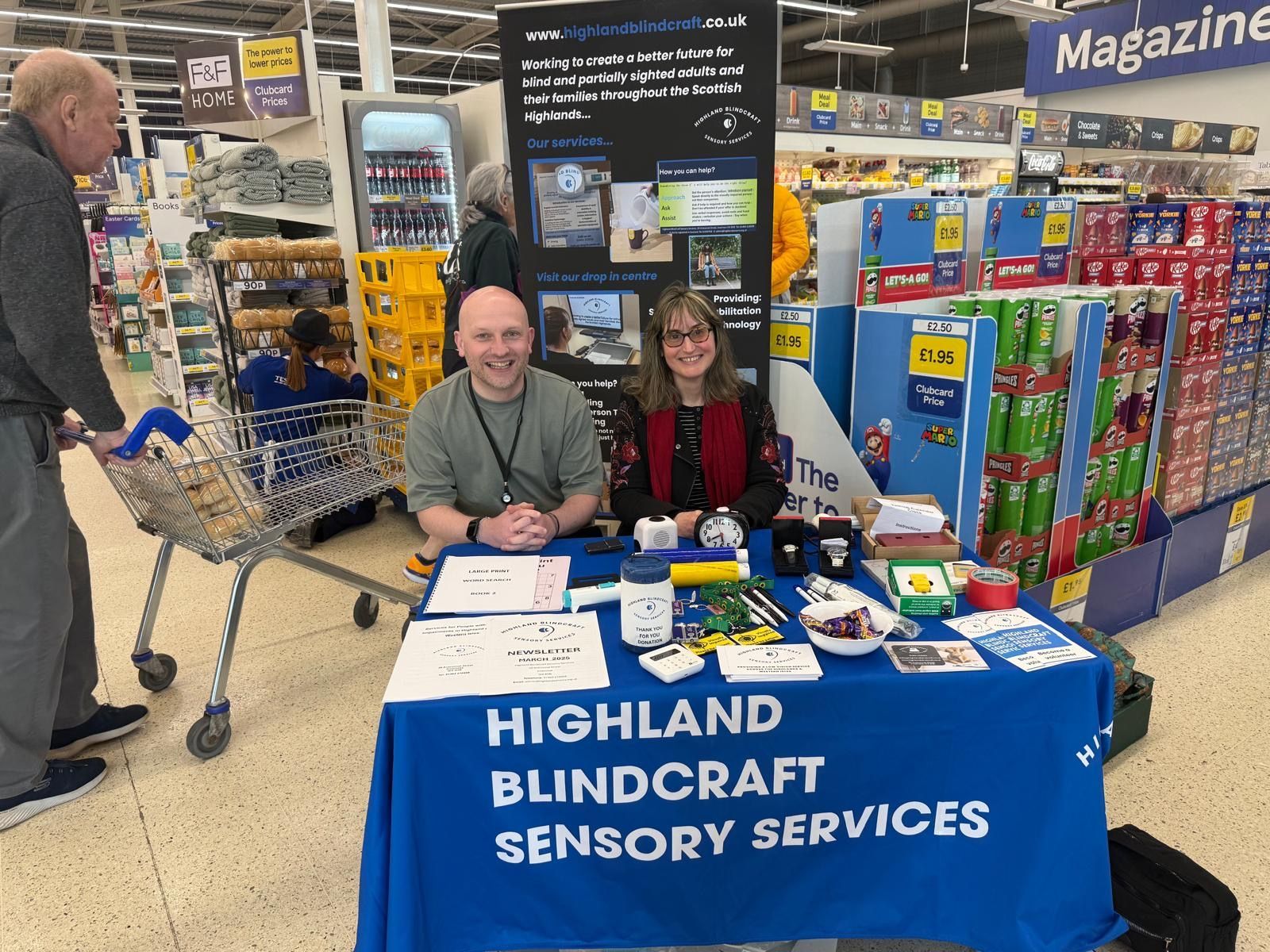 Two people sit at a table, promoting Highland BlindCraft sensory services. 
