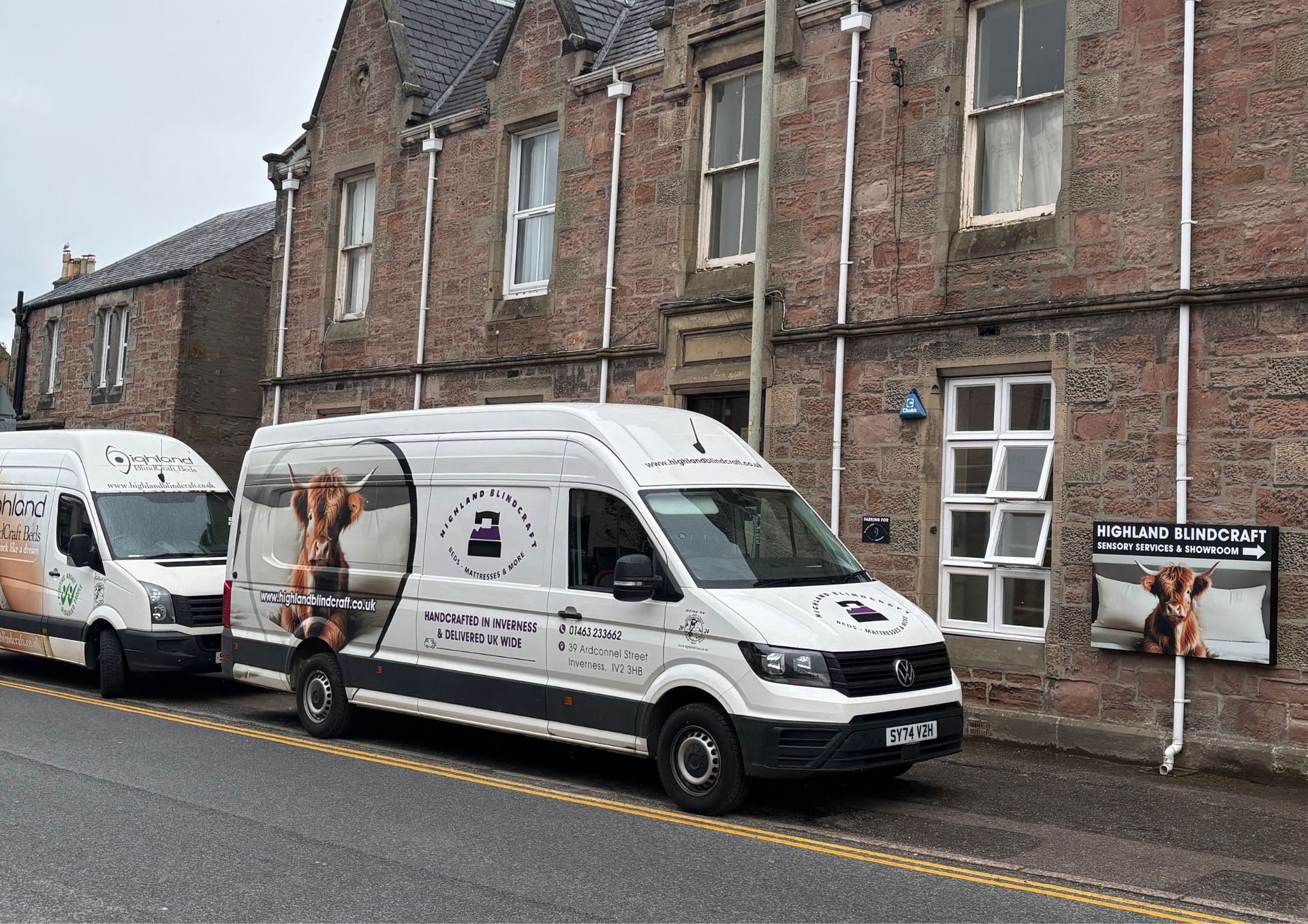Two vans are parked in front of a brick building.