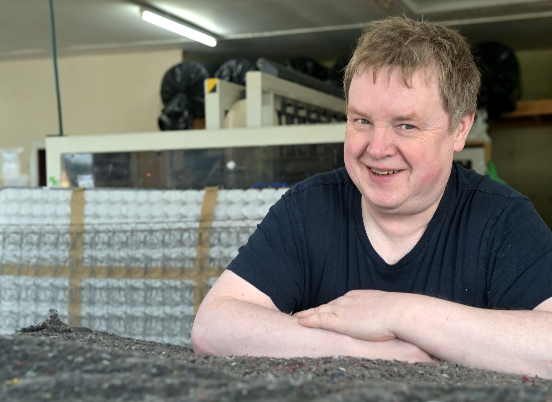 A man in a black top looks at the camera, smiling. 