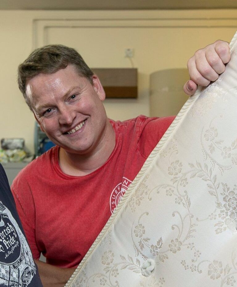 A man in a red top smiles at the camera. 