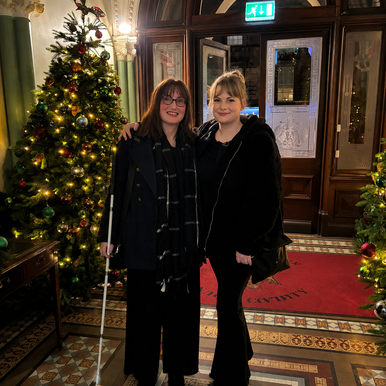 2 women smile beside a christmas tree