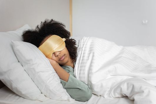A woman in bed with a sleep mask on