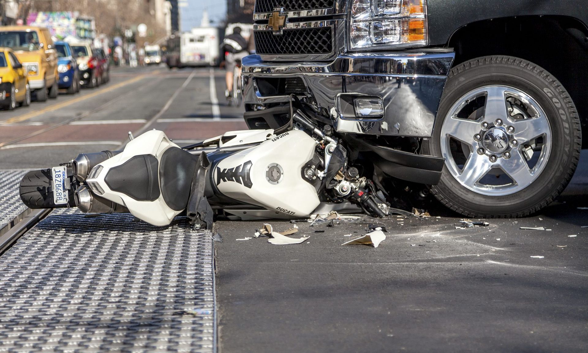 A motorcycle is laying on the ground next to a truck.