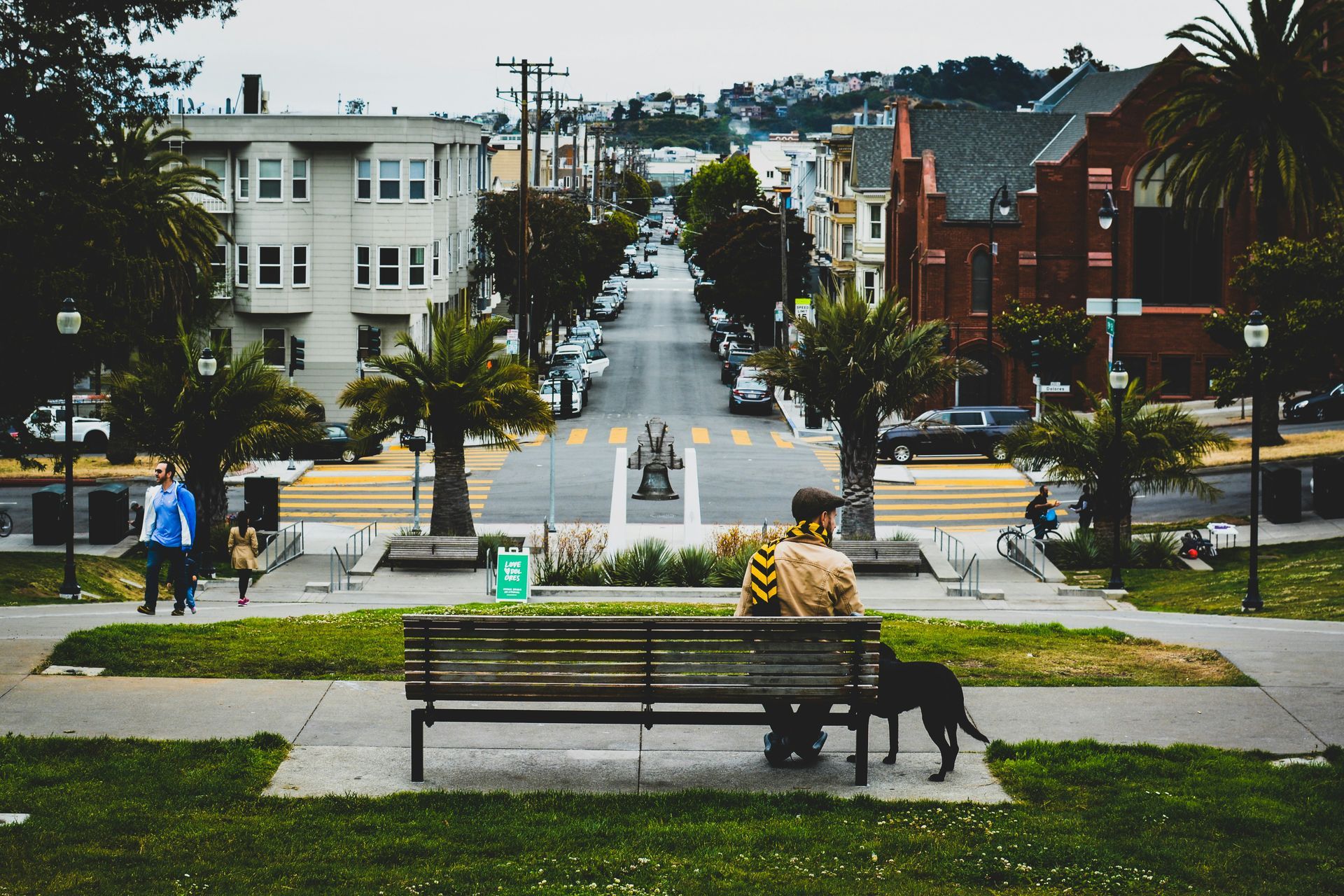 A man sits on a park bench with his dog