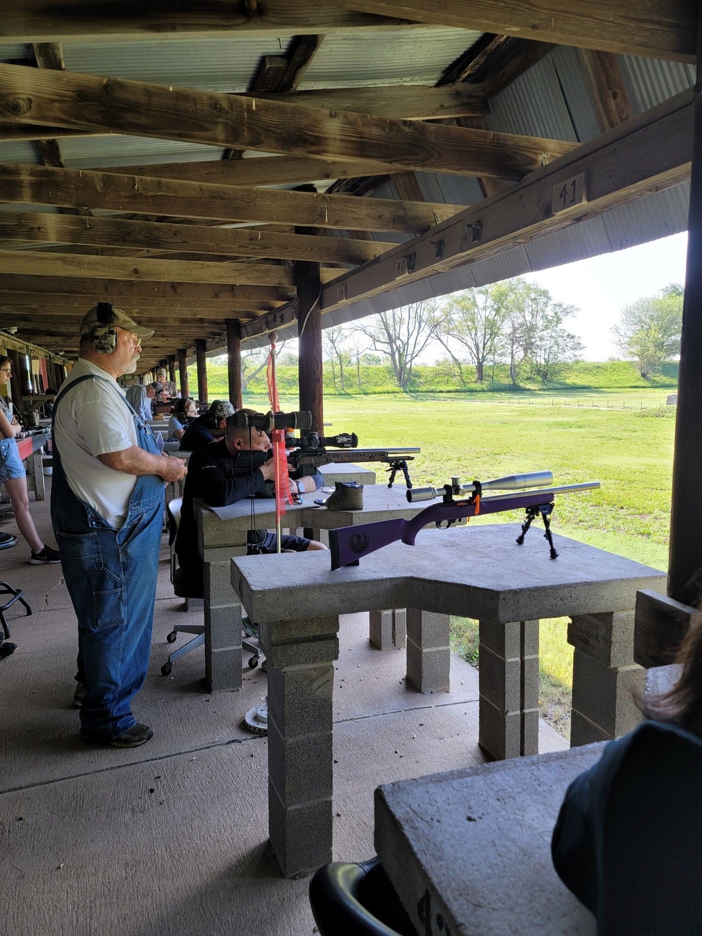 man standing in overalls wearing ear protection at gun range