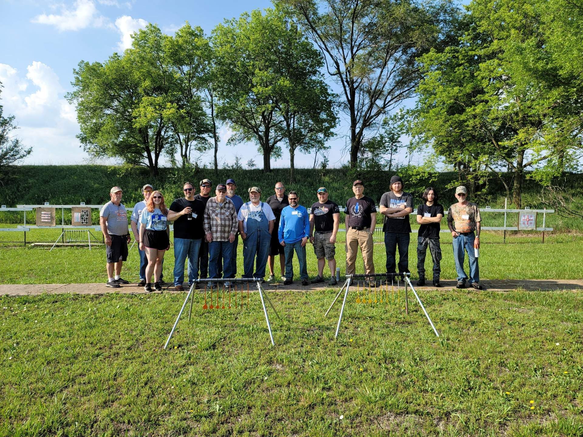 group of men and women posing for camera at gun range