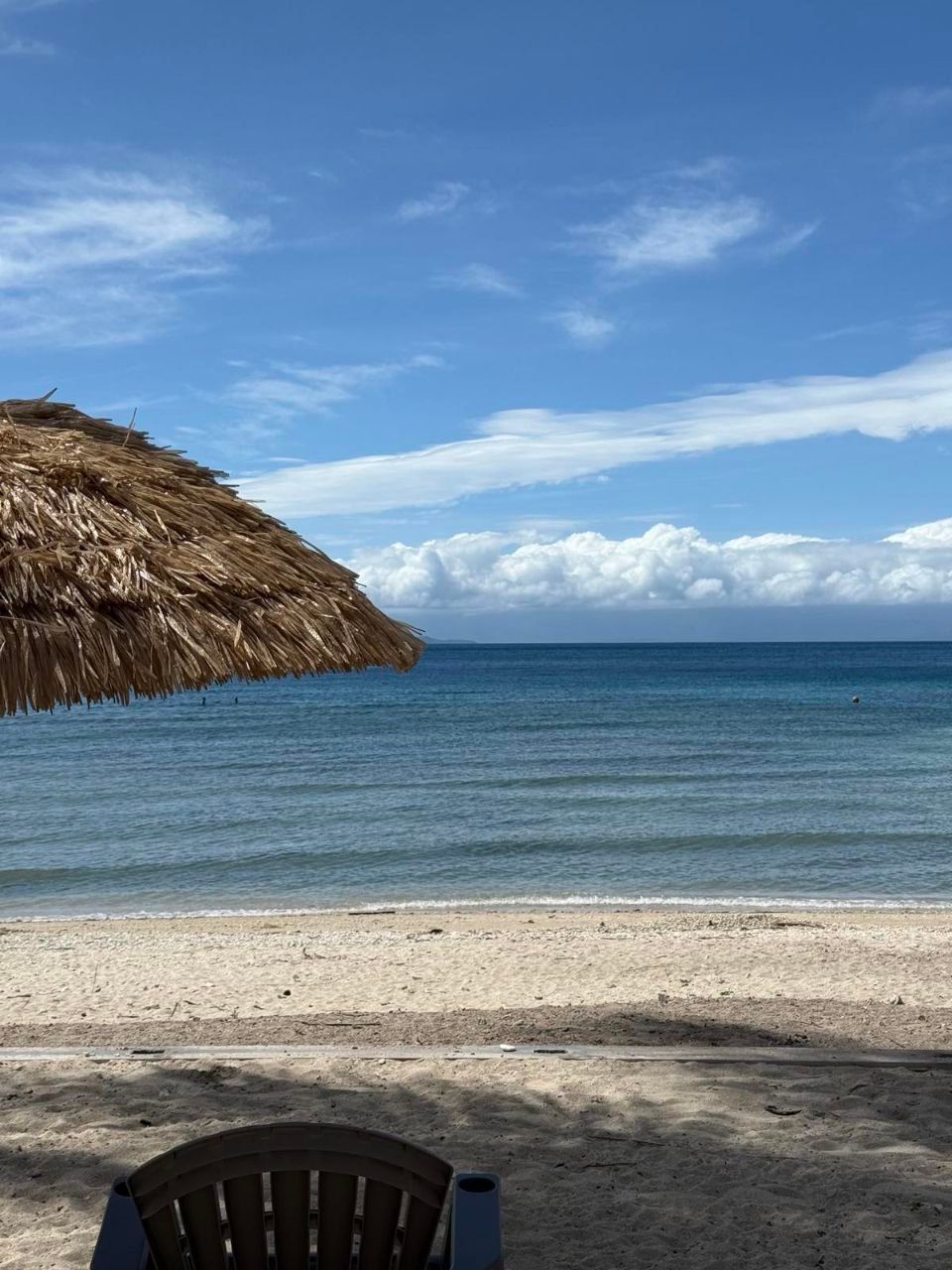 A chair and umbrella on a beach with a view of the ocean.