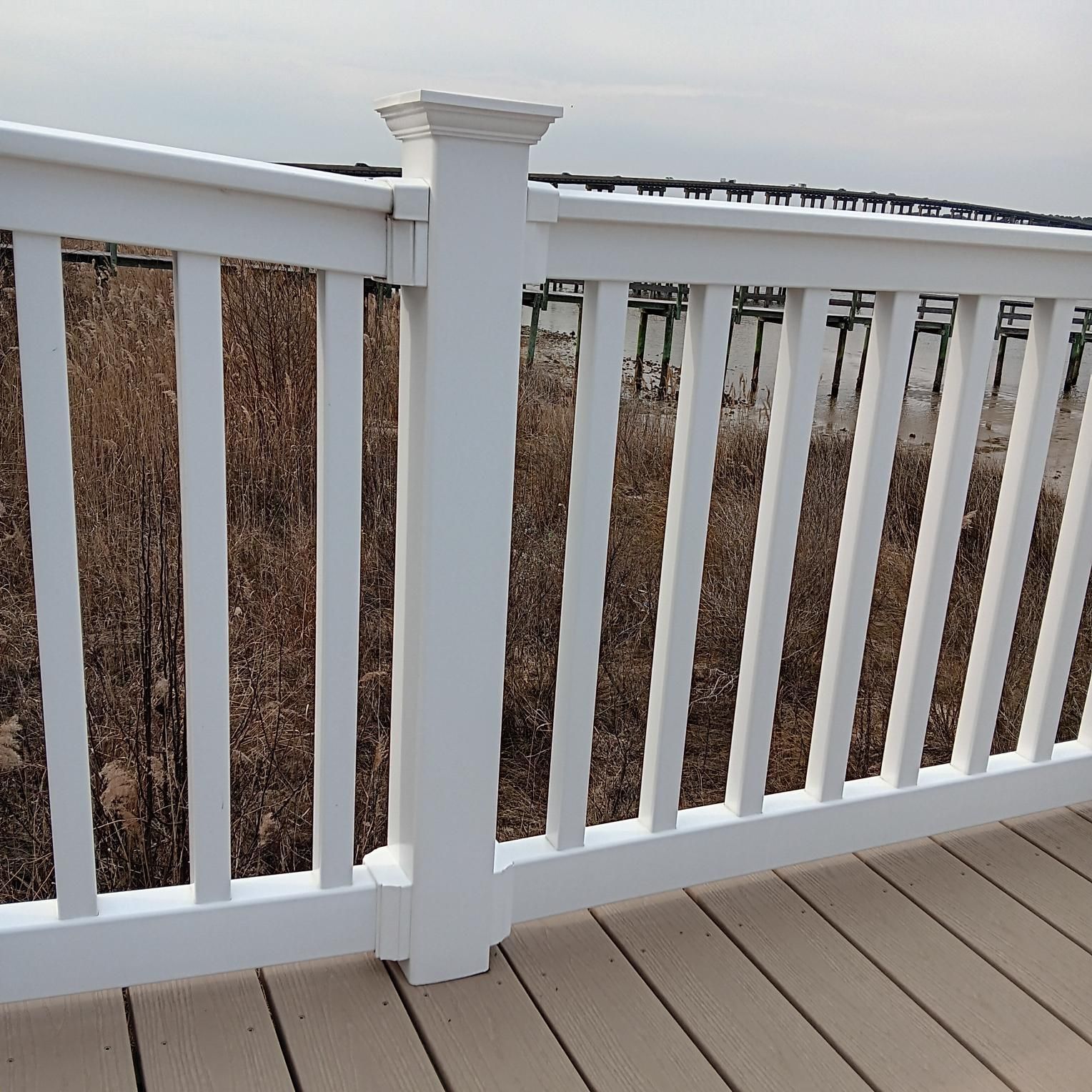 White railing on a deck overlooking water and marsh.