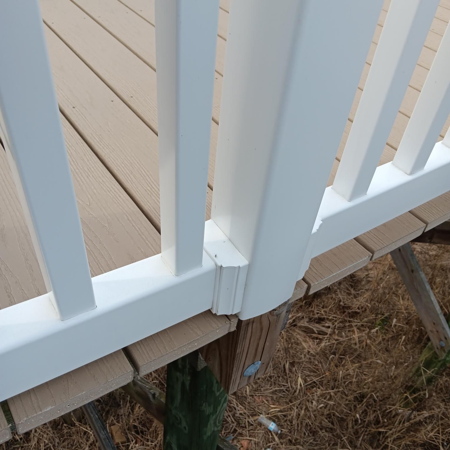 White railing with vertical balusters and deck planks; a wooden post is visible below.