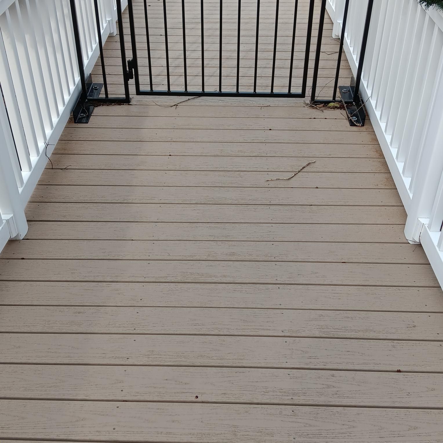 Wooden deck with white railings and a black metal gate.