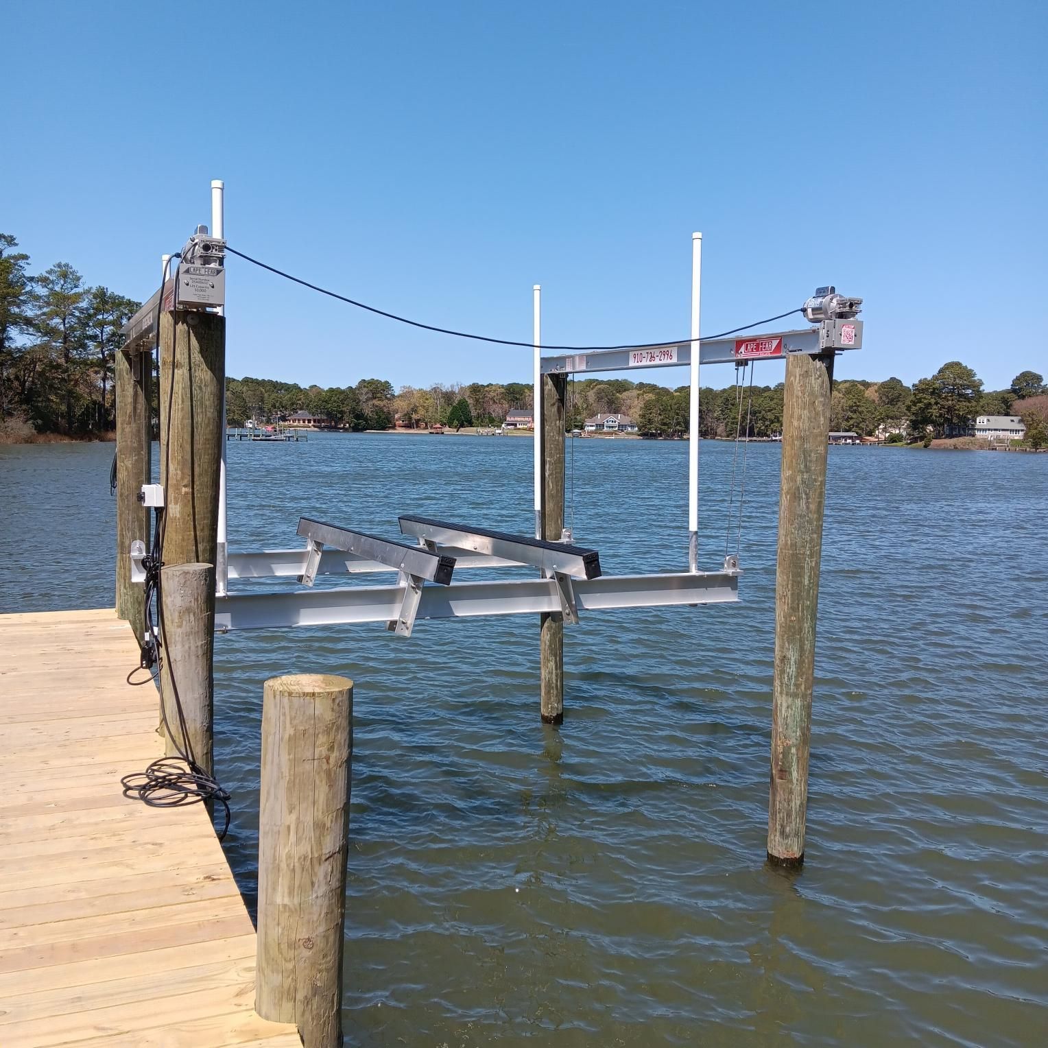 Boat lift on a dock, partially submerged in water, under a blue sky.