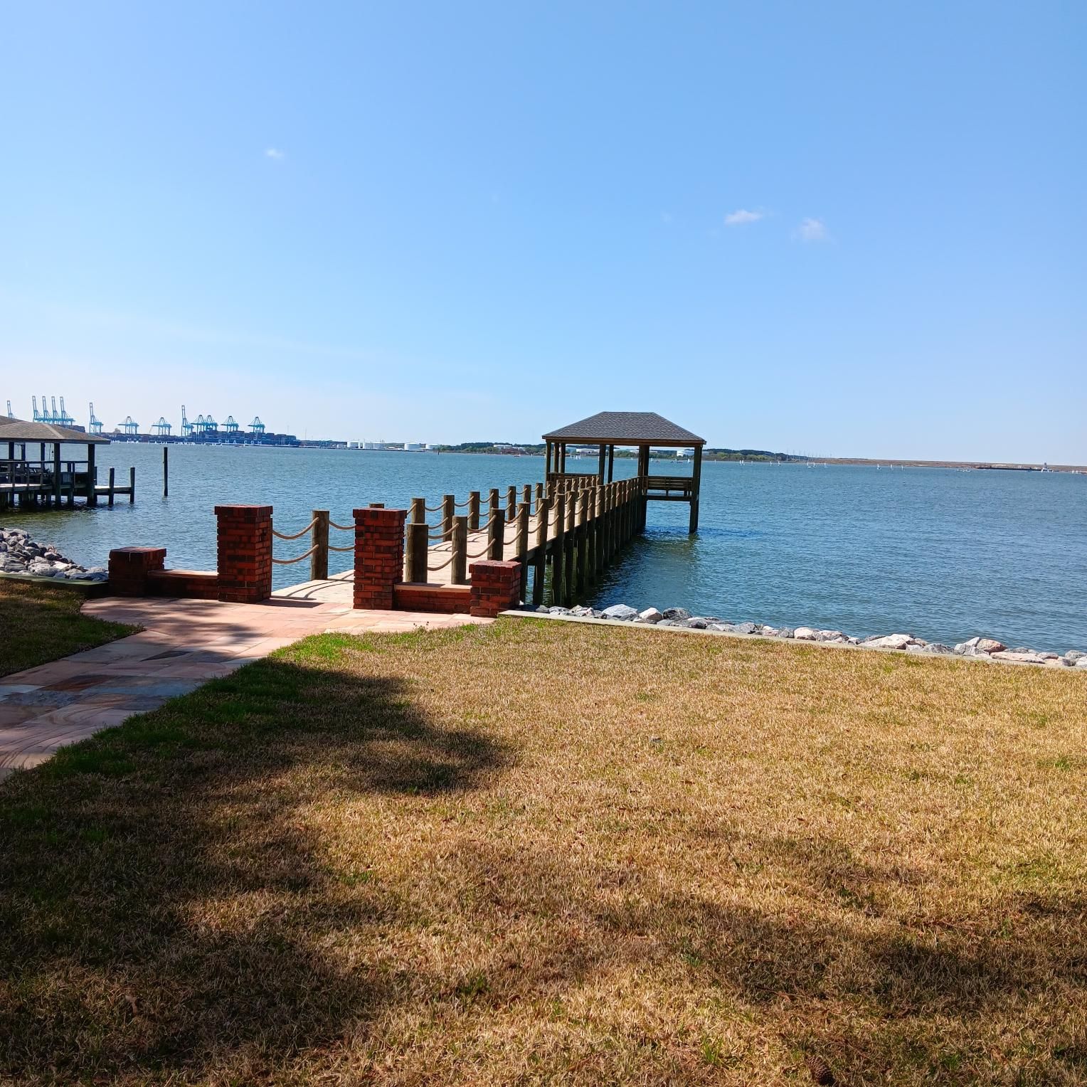 Wooden pier with gazebo extends into a body of water on a sunny day.