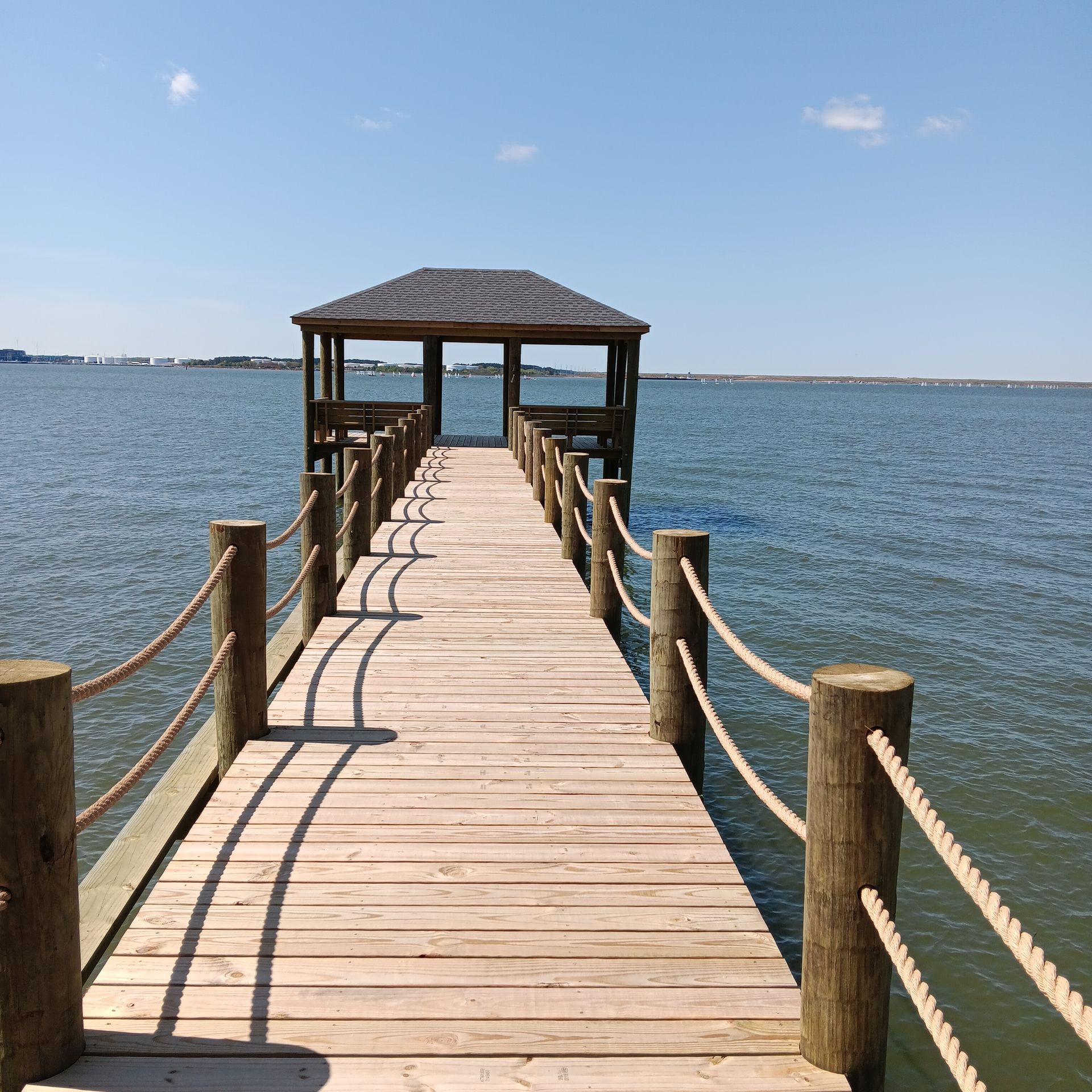 Wooden docks extend into murky water, alongside grassy bank and trees.