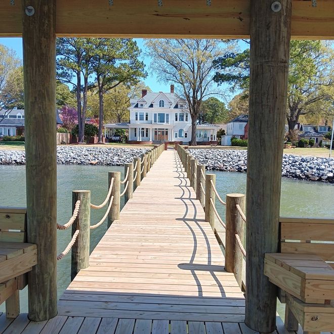 Boat lift on a wooden dock over a lake with a blue sky.