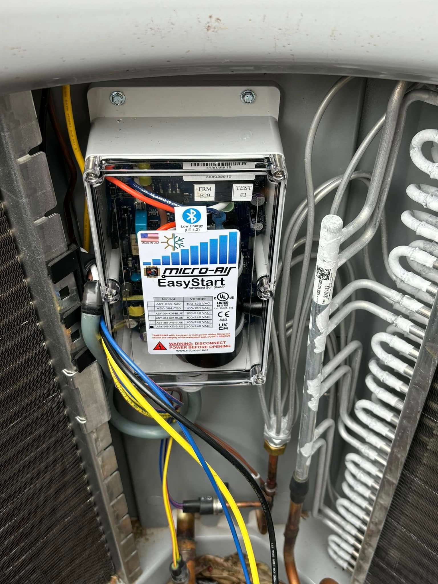 An open control box on an outdoor HVAC unit, showing wires and a Micro-Air EasyTouch soft starter module.