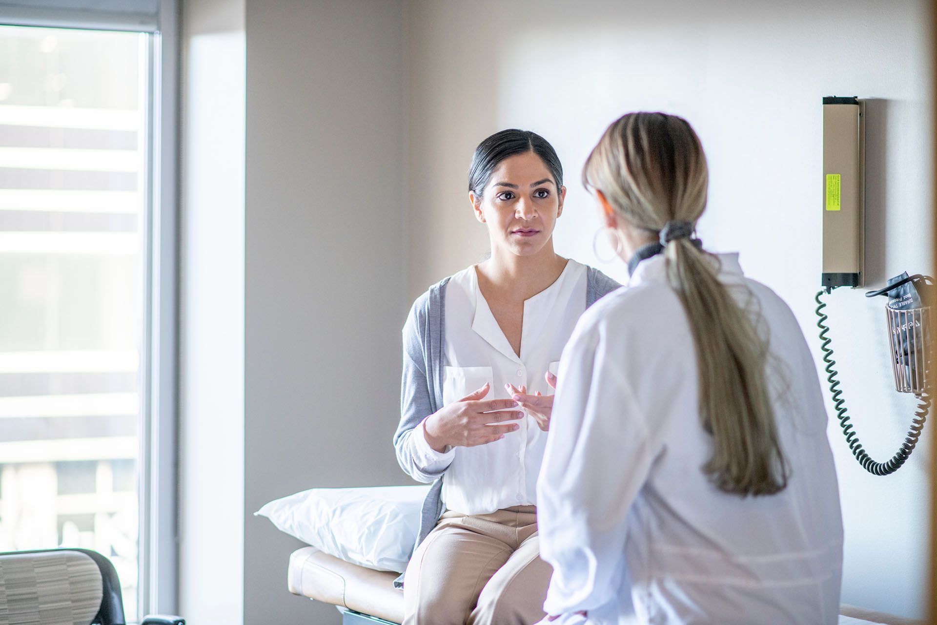A doctor is talking to a patient who is sitting on an examination table