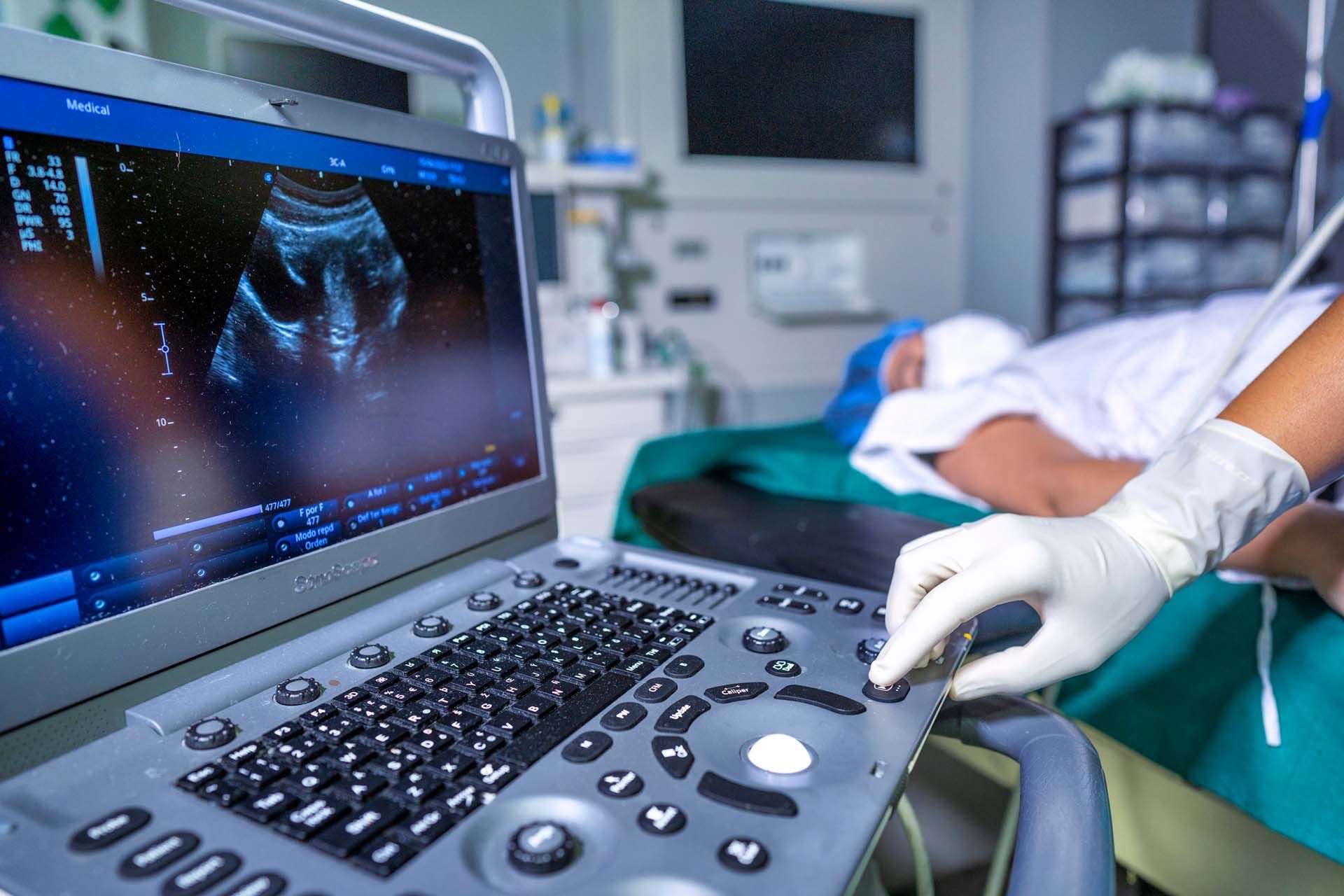 A person is using an ultrasound machine in a hospital room