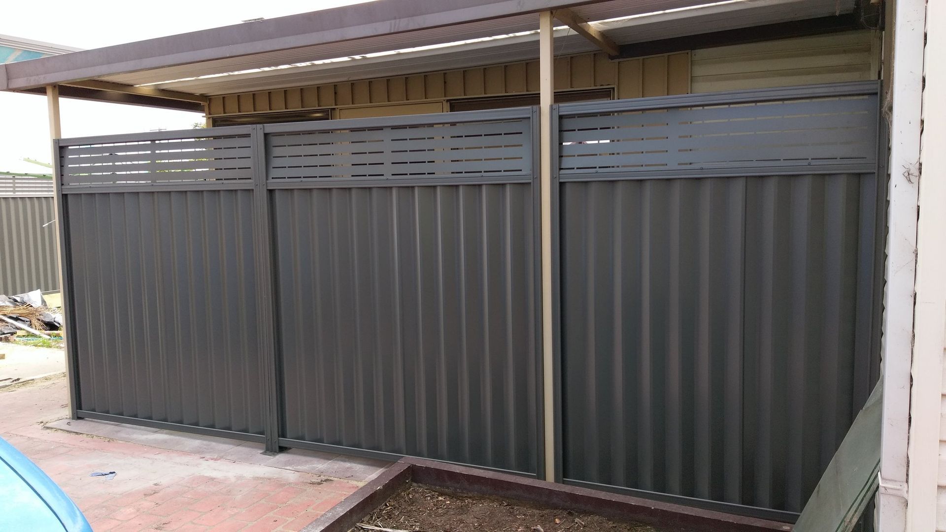 A fence with a roof and a car parked in front of it.