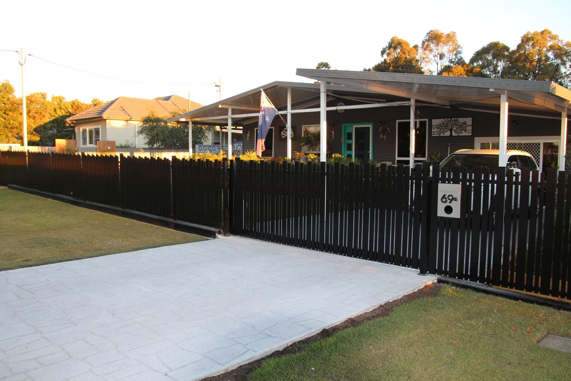 A black fence surrounds a house with a car parked in front of it