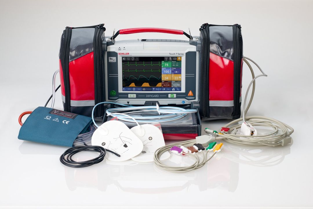 A defibrillator is sitting on a table next to a bag.