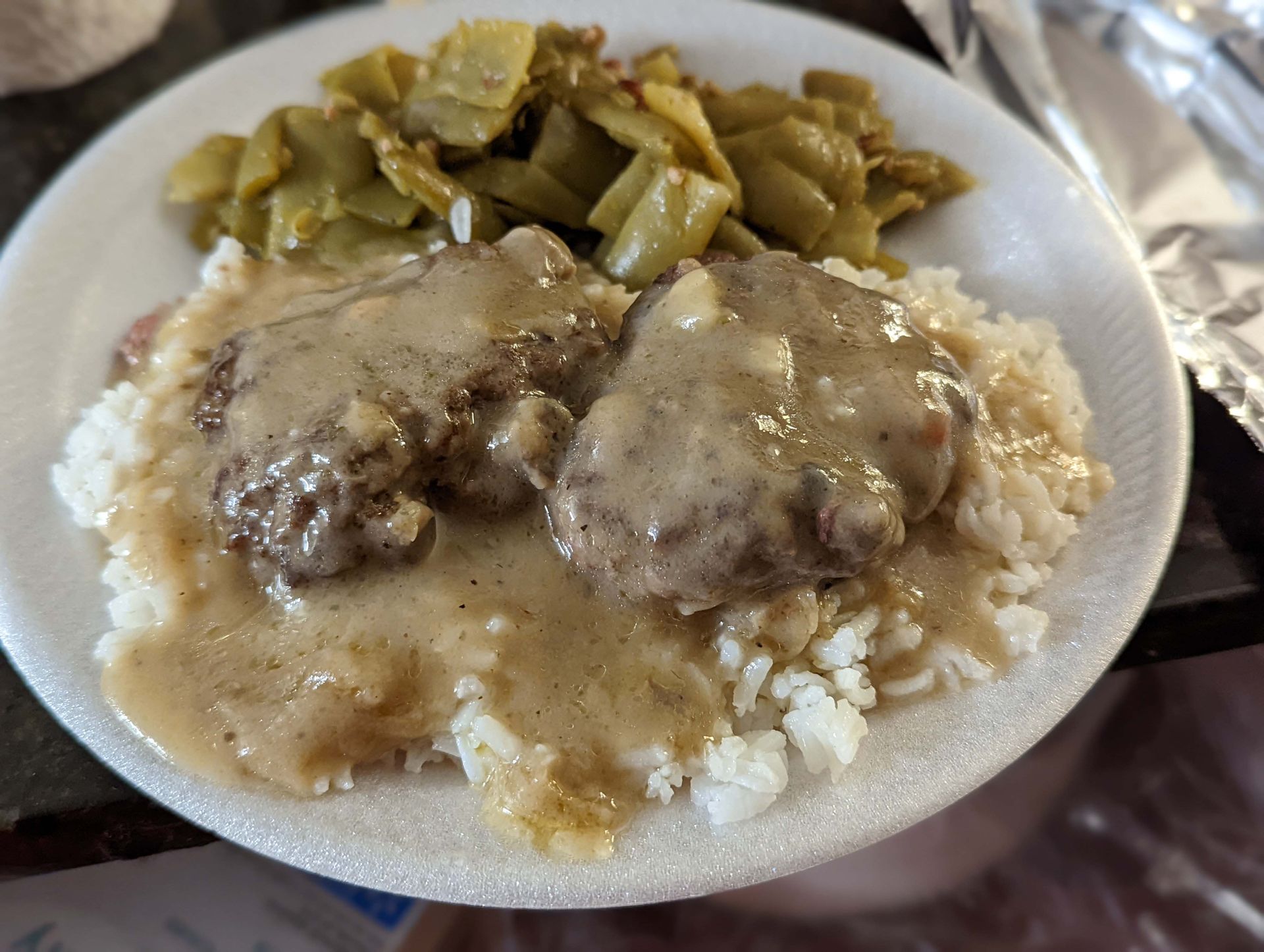 A white plate topped with meatballs rice and green beans