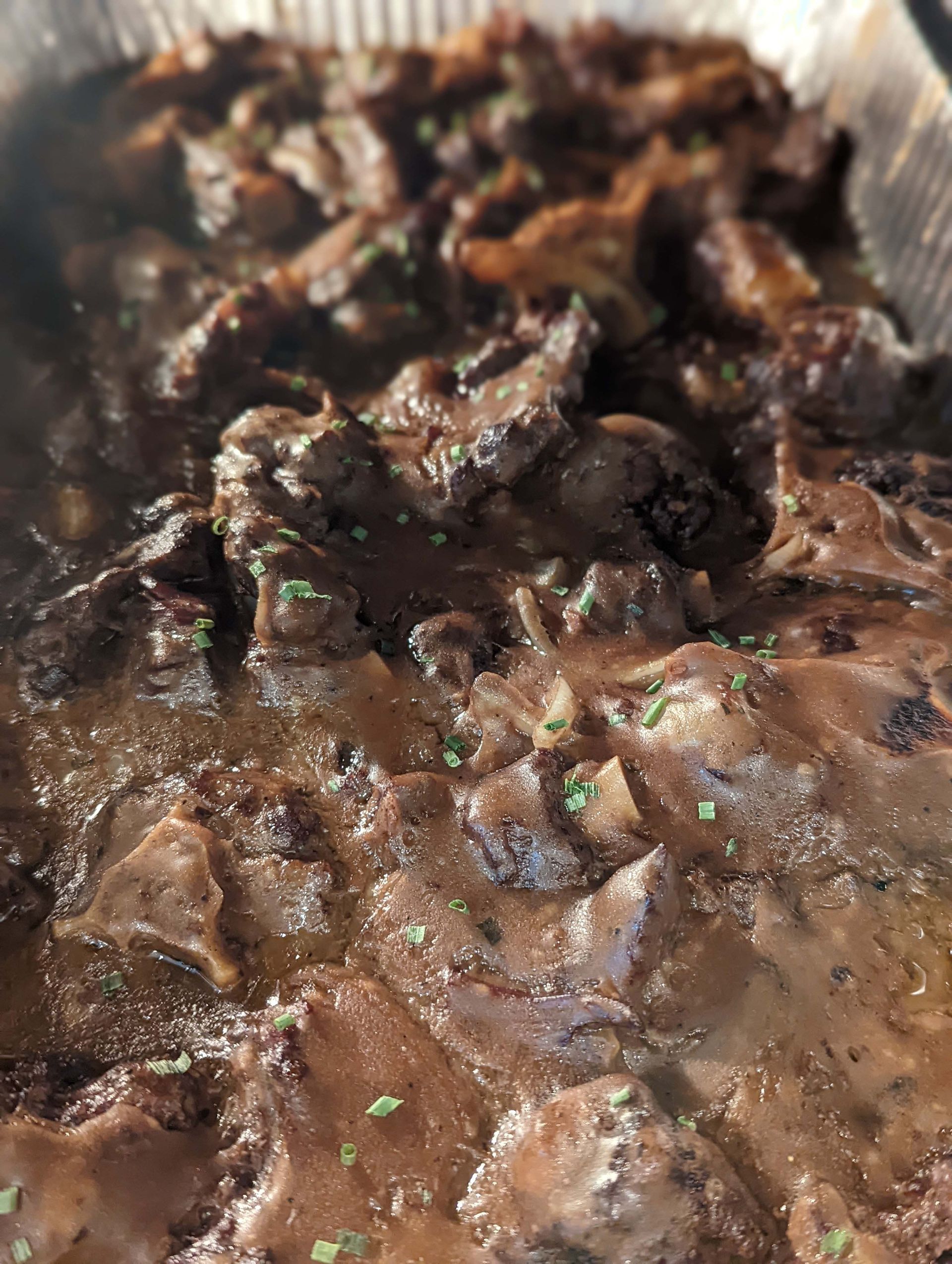 A close up of a casserole dish filled with meat and sauce.