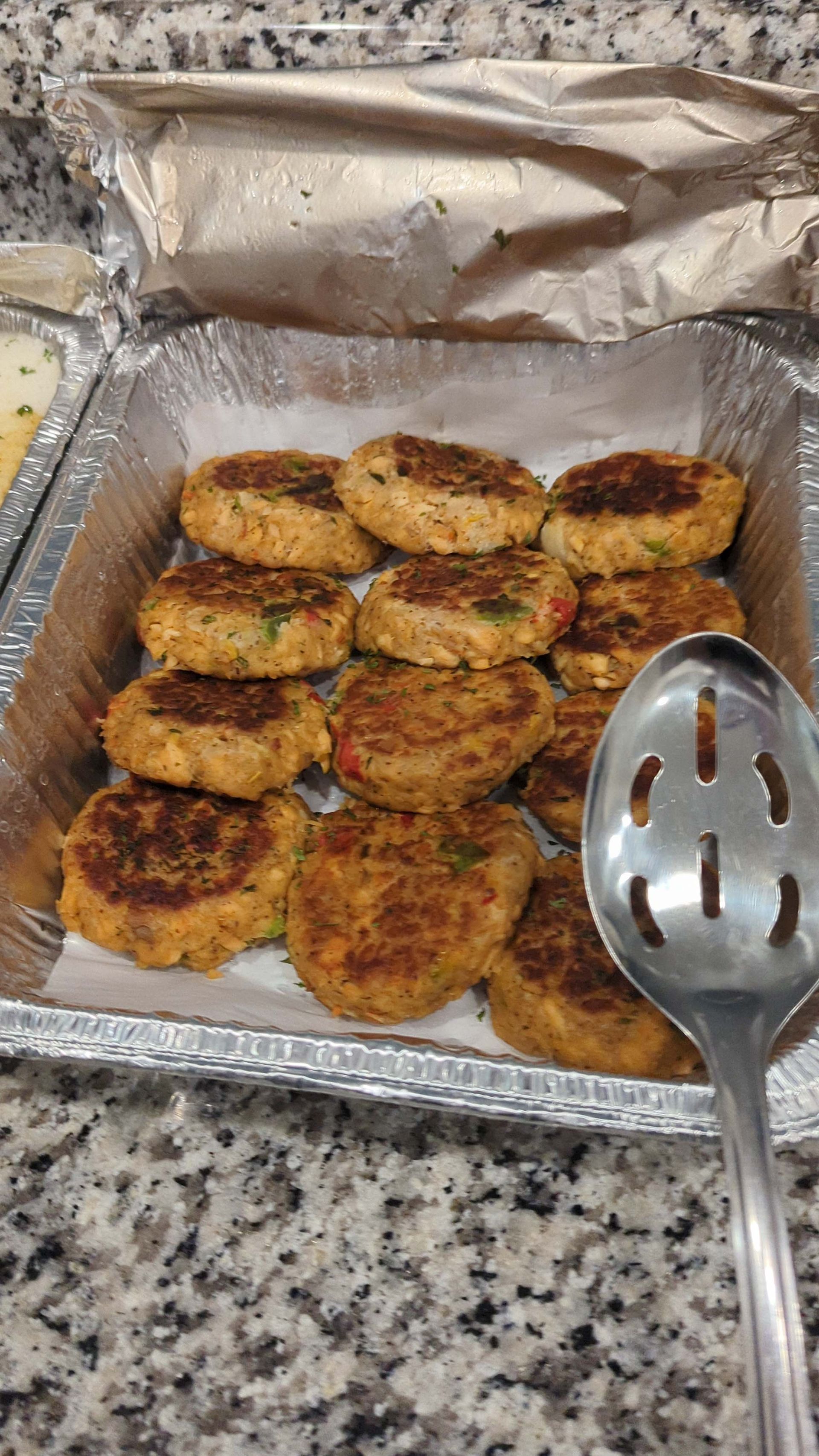 A tray of food with a spoon in it on a counter.