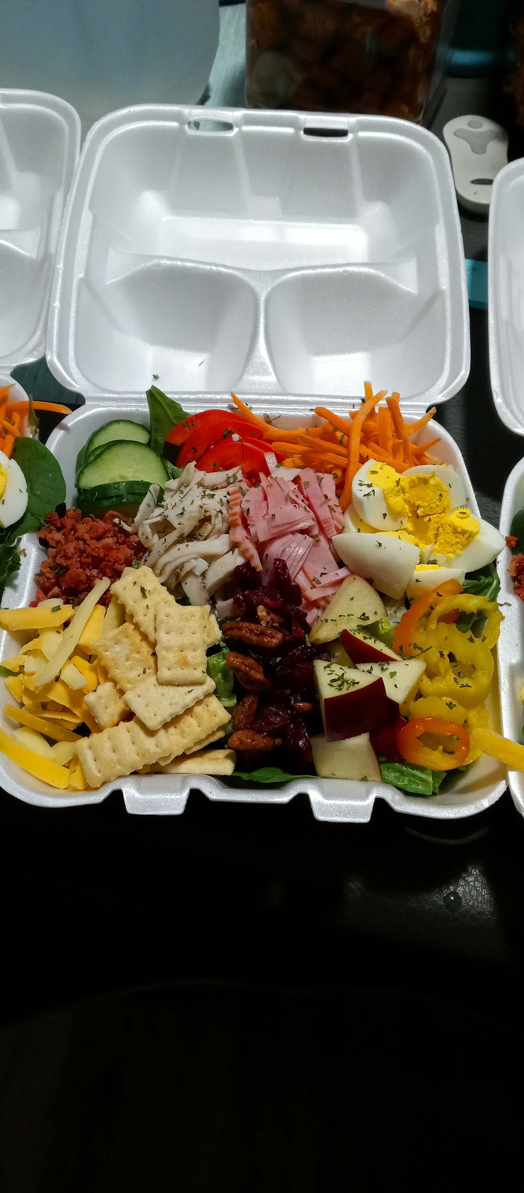 A styrofoam container filled with a variety of food on a table.
