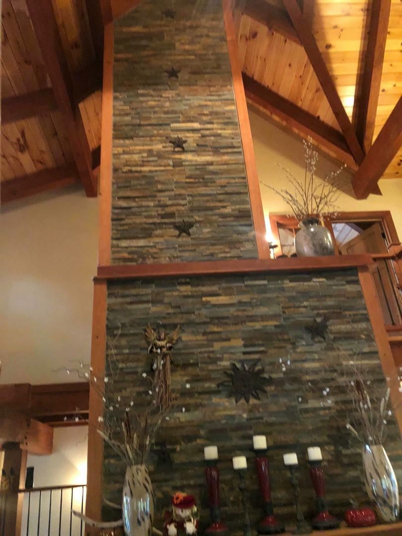 A large stone fireplace with candles on it in a living room