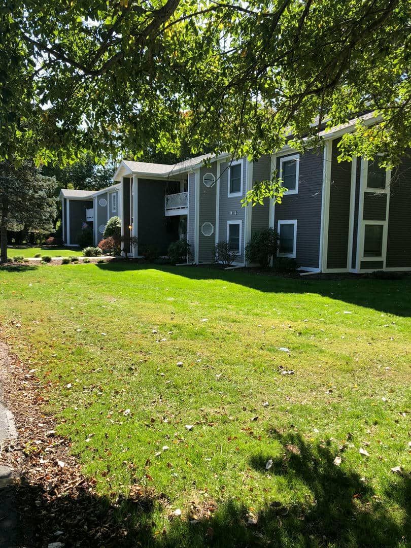 A row of apartment buildings sitting next to each other on a lush green lawn.