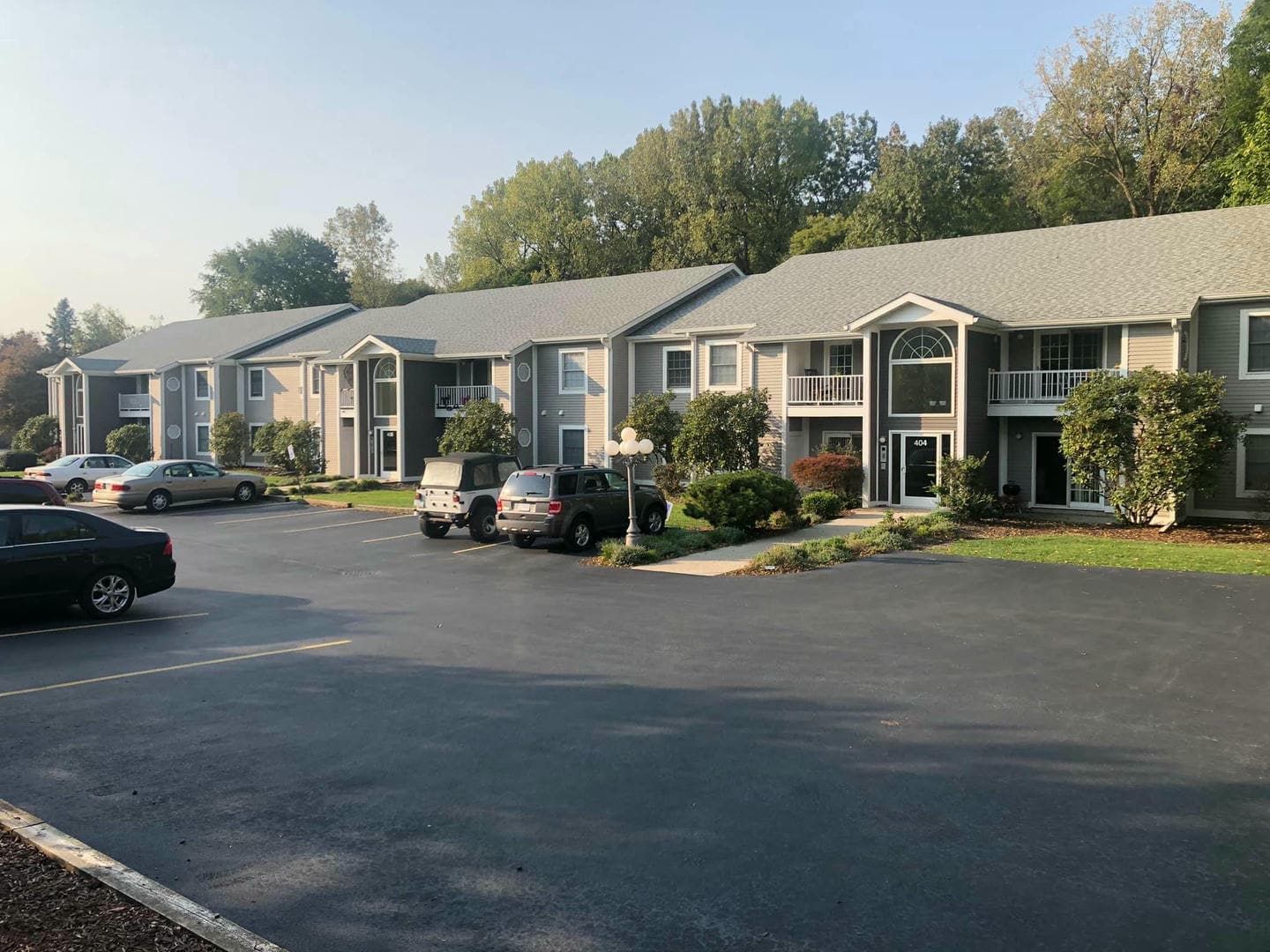 A row of apartment buildings with cars parked in front of them.
