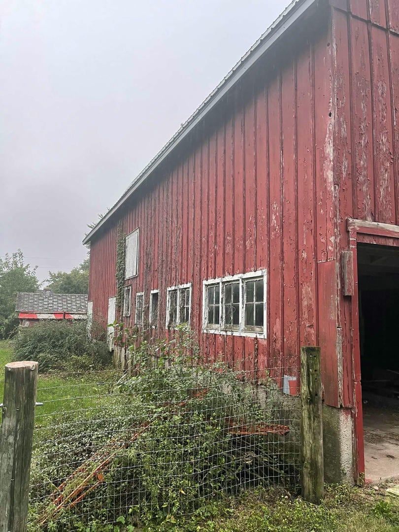 A red barn is sitting in the middle of a grassy field.