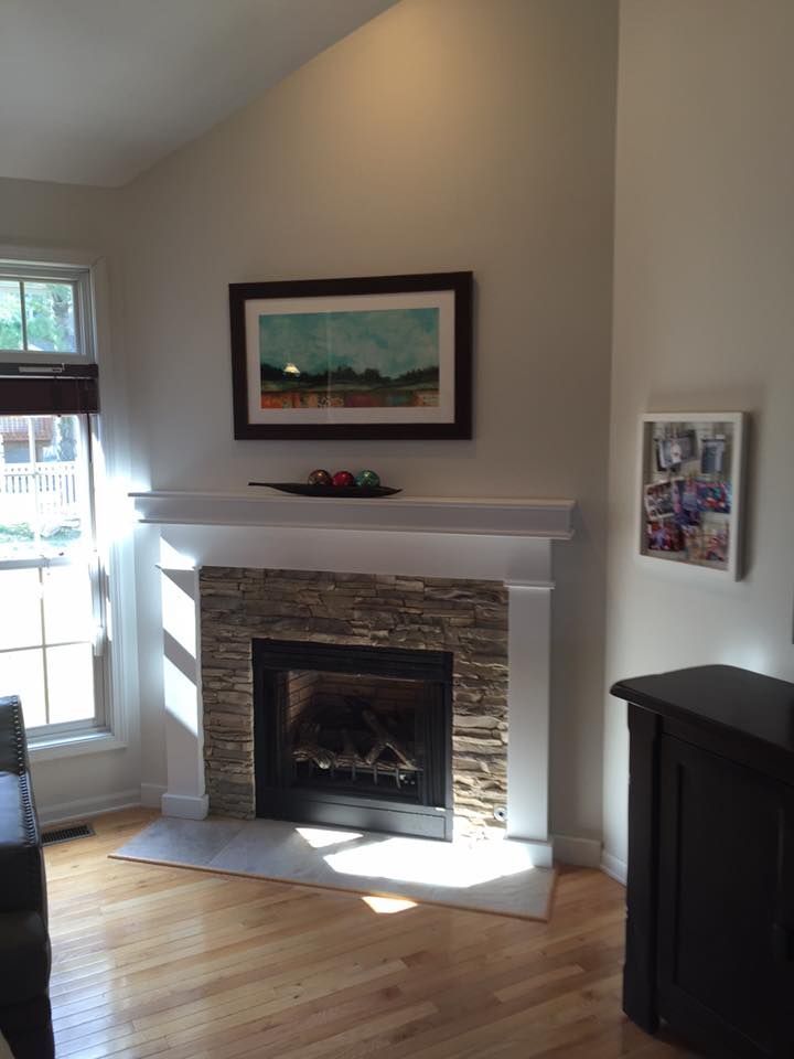 A living room with a fireplace and a picture on the wall above it.