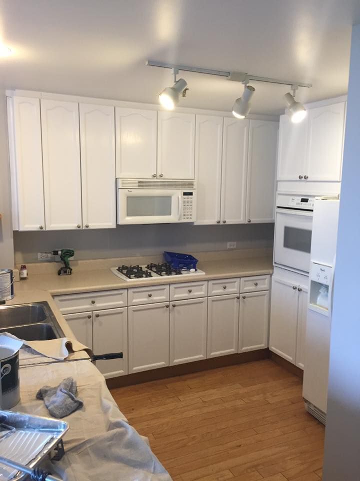 A Kitchen With White Cabinets , A Stove , A Microwave , A Sink , And A Refrigerator