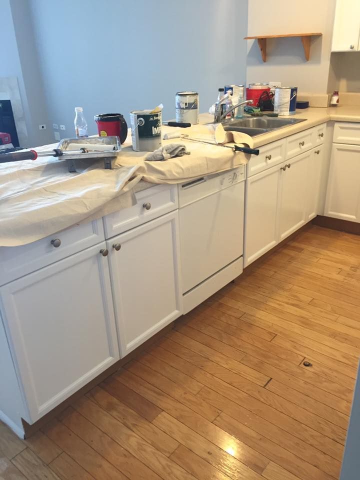 A Kitchen With White Cabinets And Hardwood Floors Is Being Painted